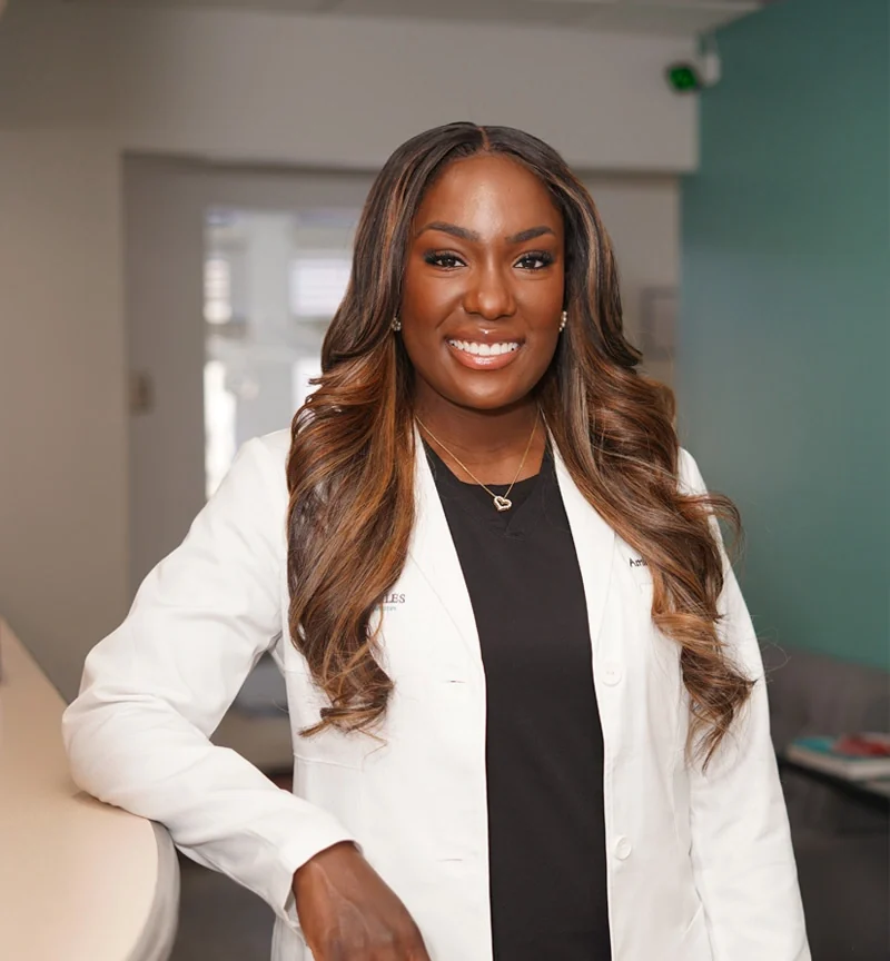 Dr. Aminat Osuji, DDS, owner of Designer Smiles, in a white coat.