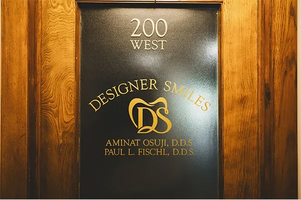 The door of Suite 200 West, lettered Designer Smiles, Aminat Osuji, D.D.S. and Paul L. Fischl, D.D.S.