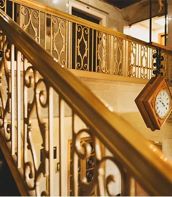 The carved brass staircase and hanging clock in the Carlson Building lobby.